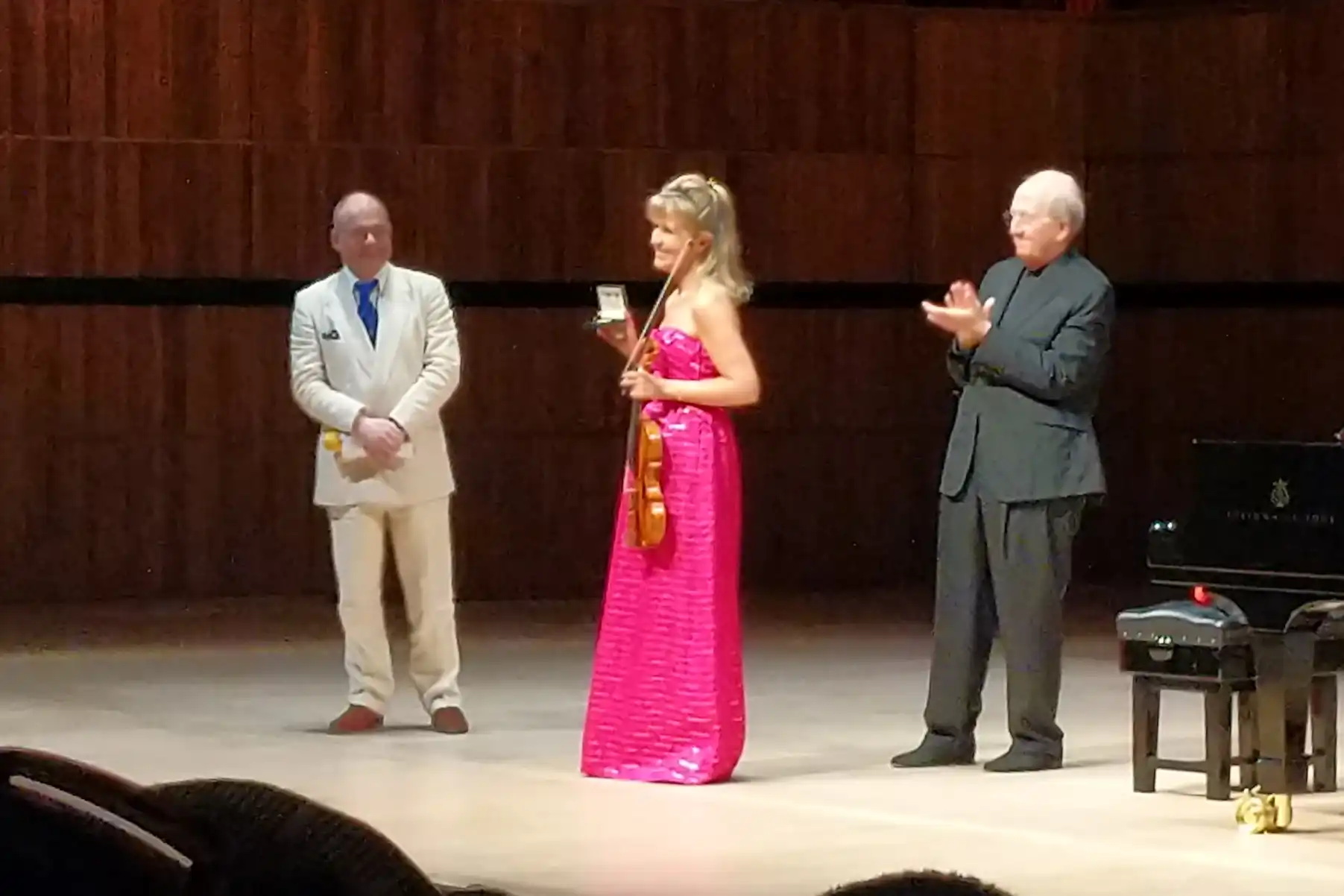 Anna-Sophie Mutter on the stage of the Royal Festival Hall. She is holding
her violin and bow in one hand, and with the other she displays the gold medal
she has just been presented.