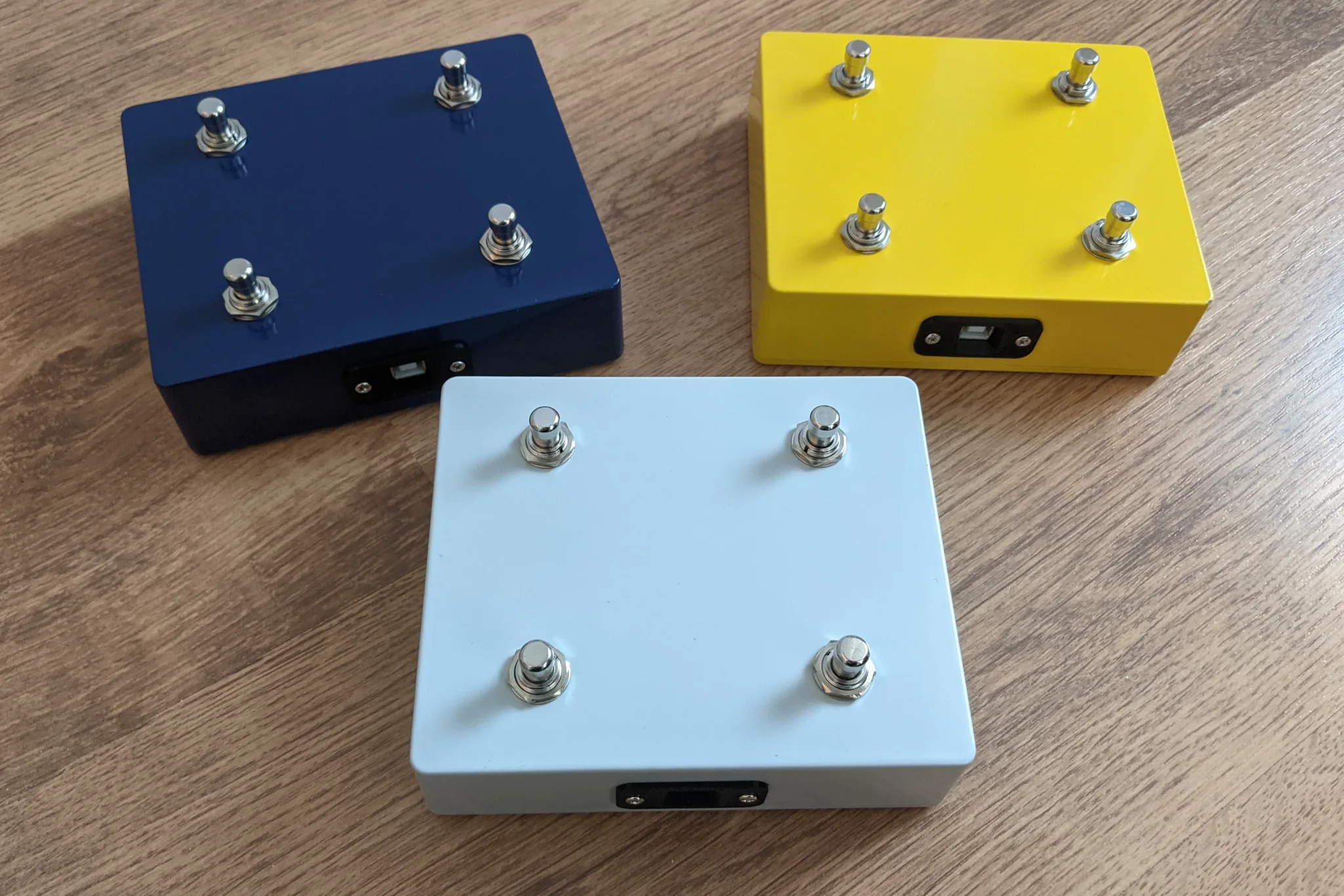 Three painted metal enclosures with four footswitches each,
and a USB connector on one side.