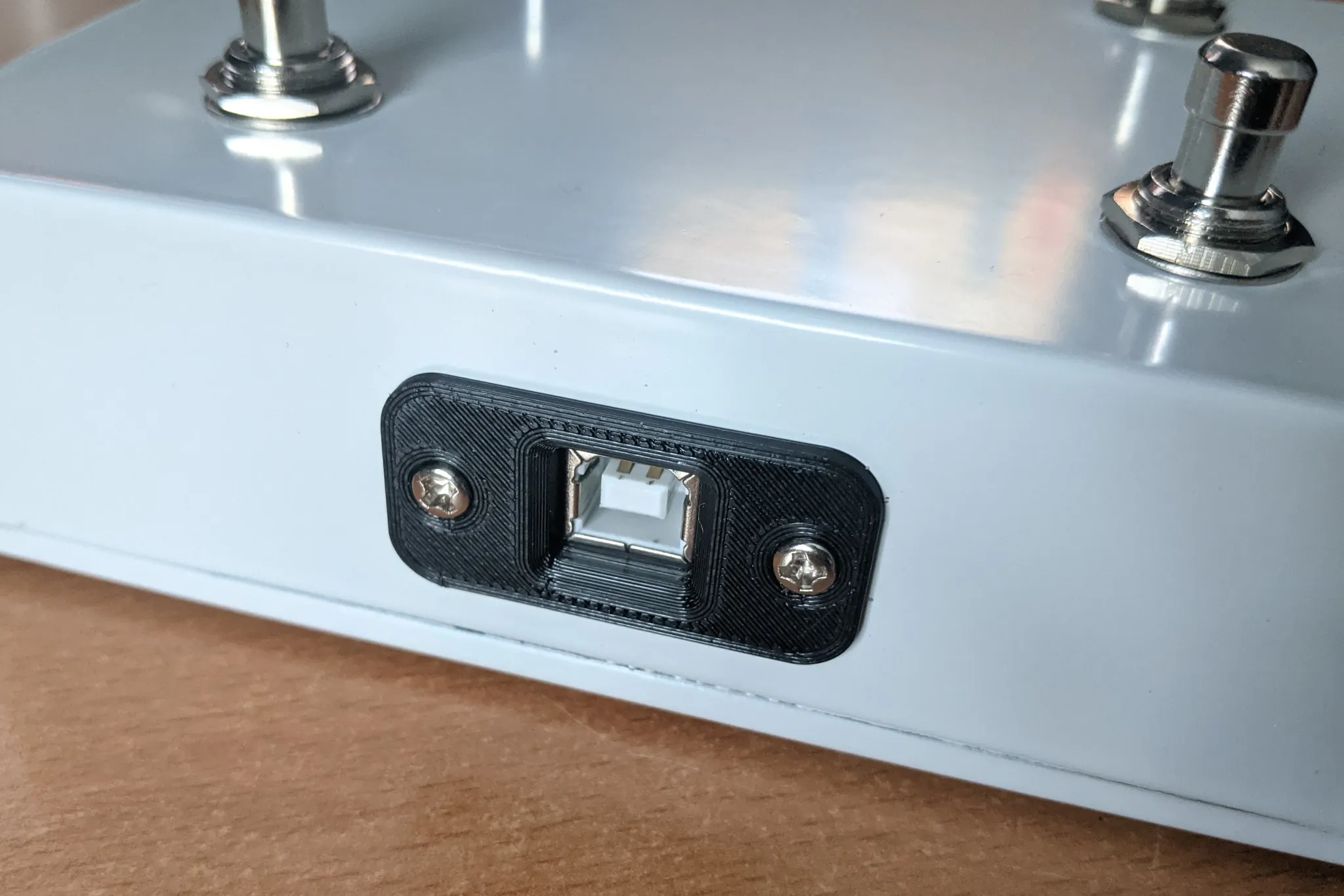 The side of a metal enclosure with a USB type B connector in a 3D-printed
black surround.