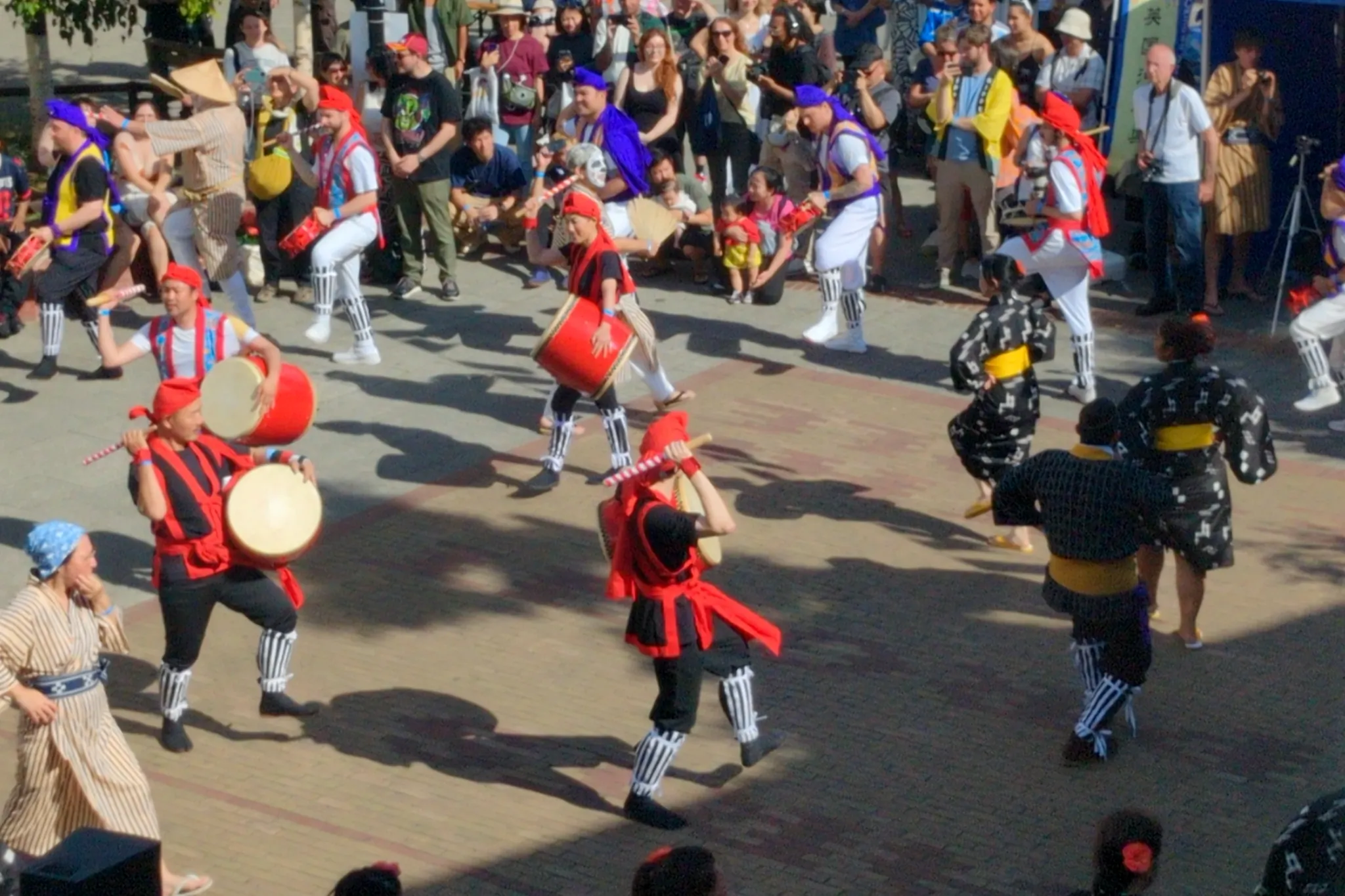Dancers with and without drums, in a circle, dressed in Okinawan costume