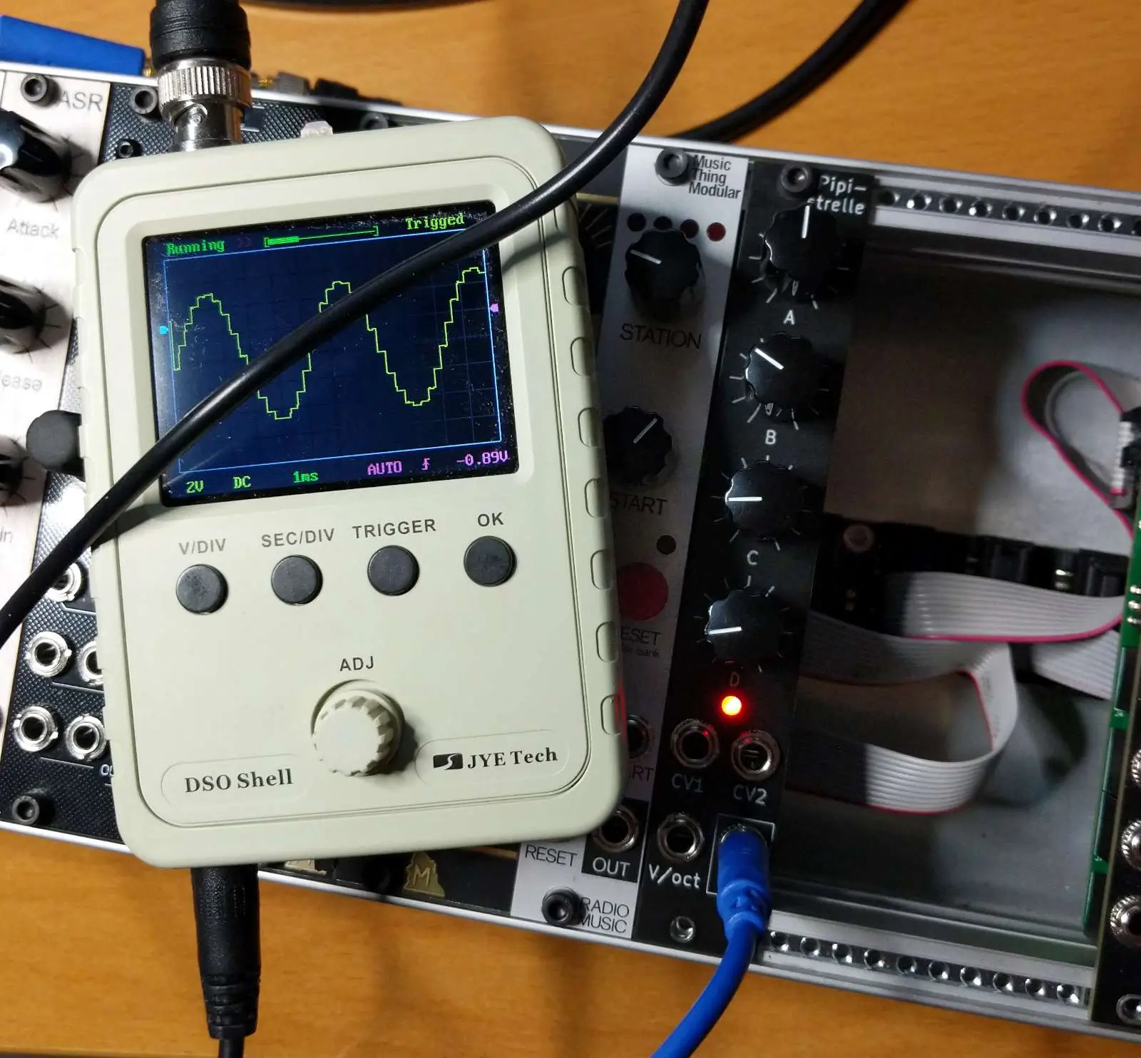 Testing a Eurorack module. A sine wave is shown on a mini oscilloscope