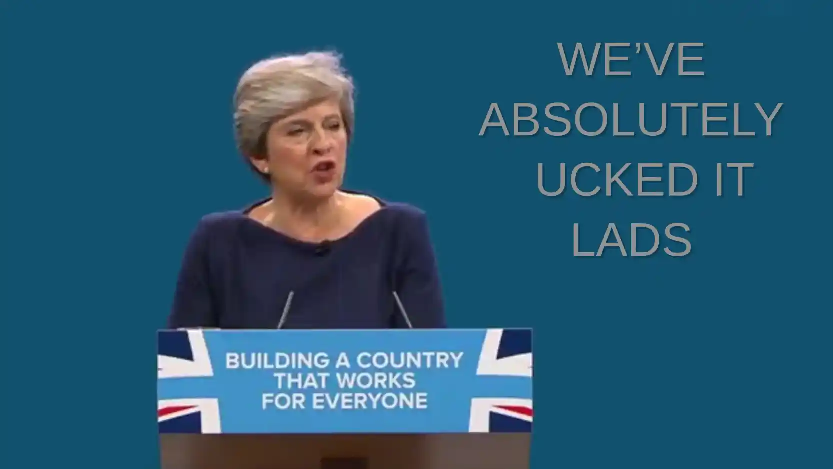 Theresa May in front of spoof conference backdrop saying 'We've absolutely ucked it lads'