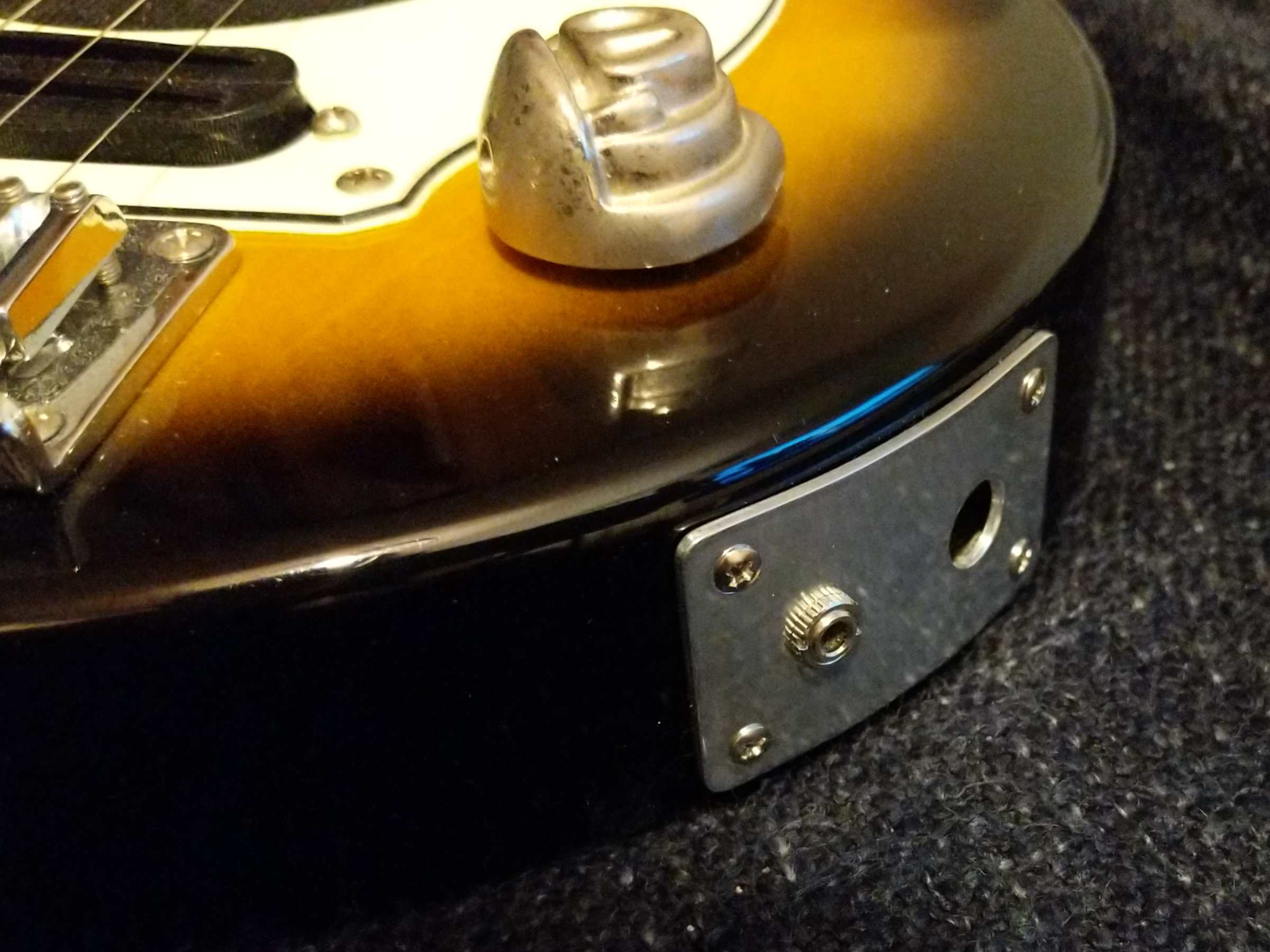 A close-up view of the jack plate fitted to the guitar. It follows the curve very closely, with only a slight gap. It's missing the jack socket.